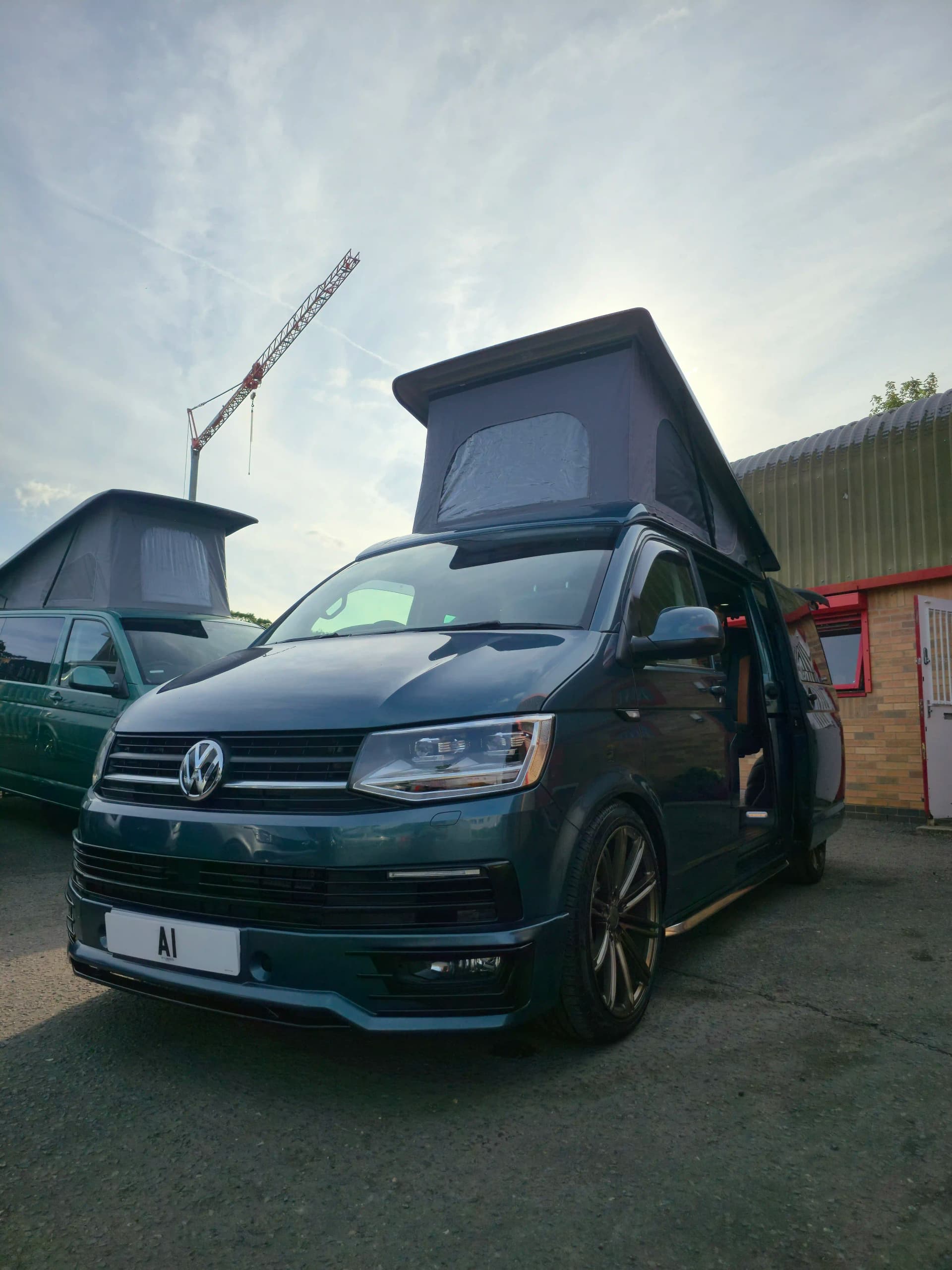 A large peugeot camper van with its door open to show the custom fittings inside.