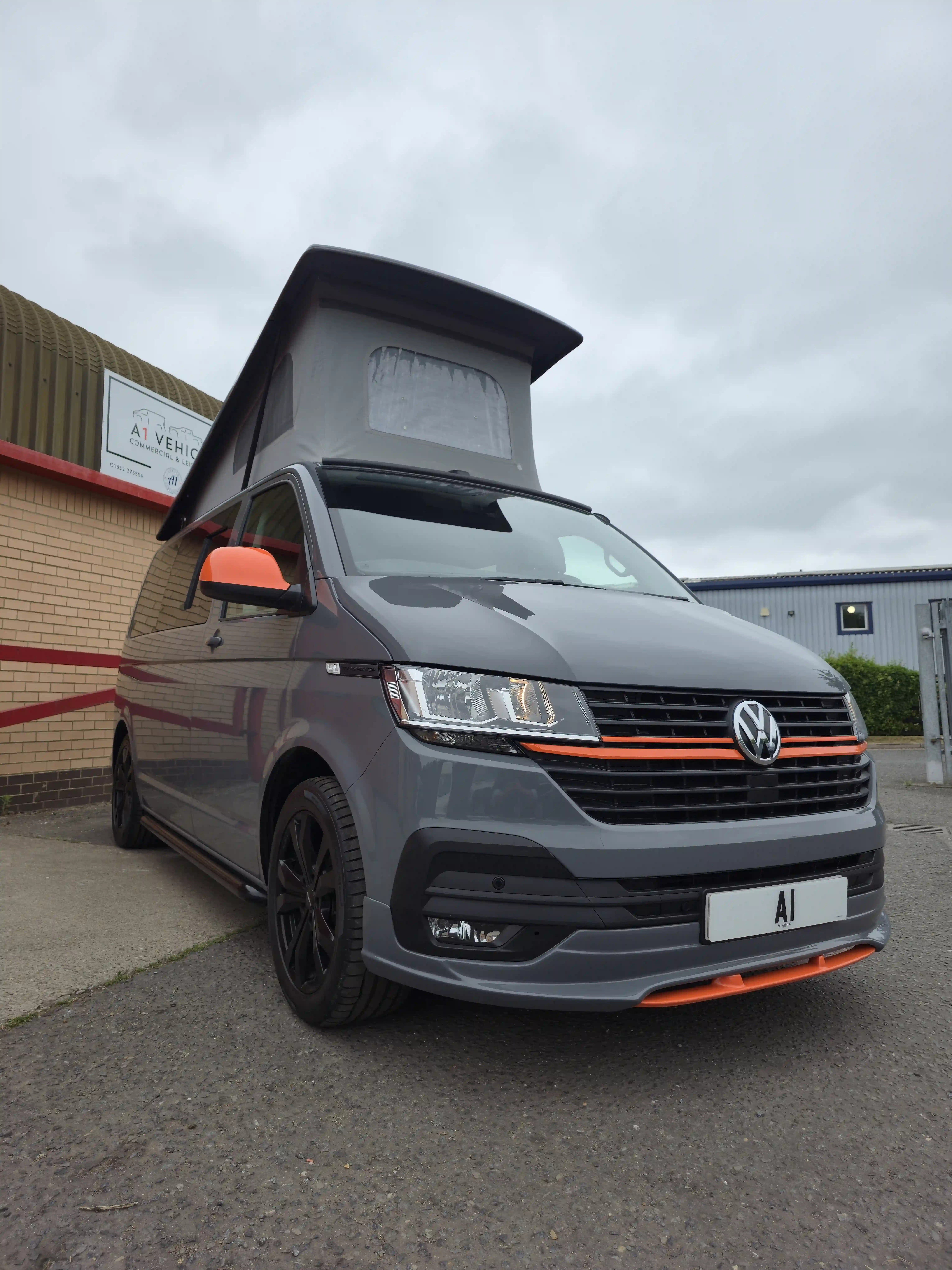 A red volkswagen van that has been converted to campervan with custom detailing.